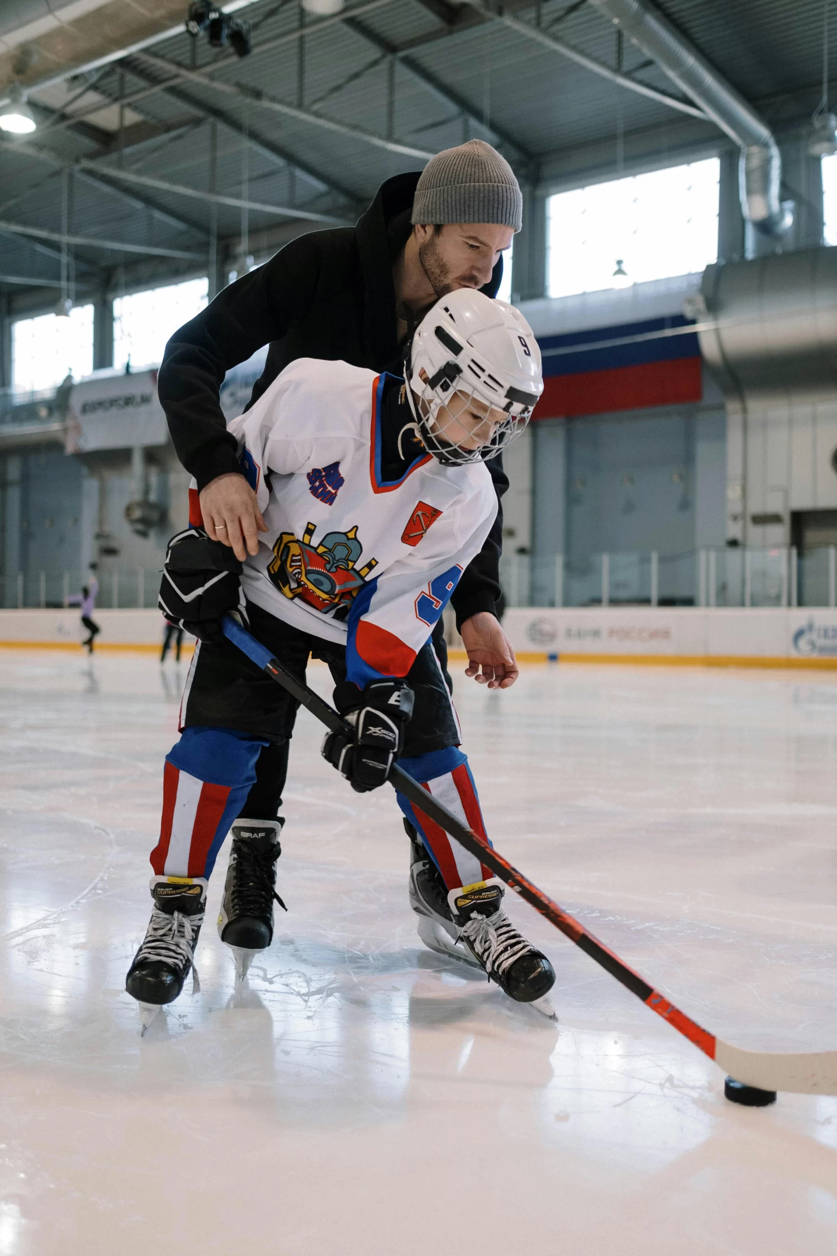 Father teaching son hockey techniques and skills.