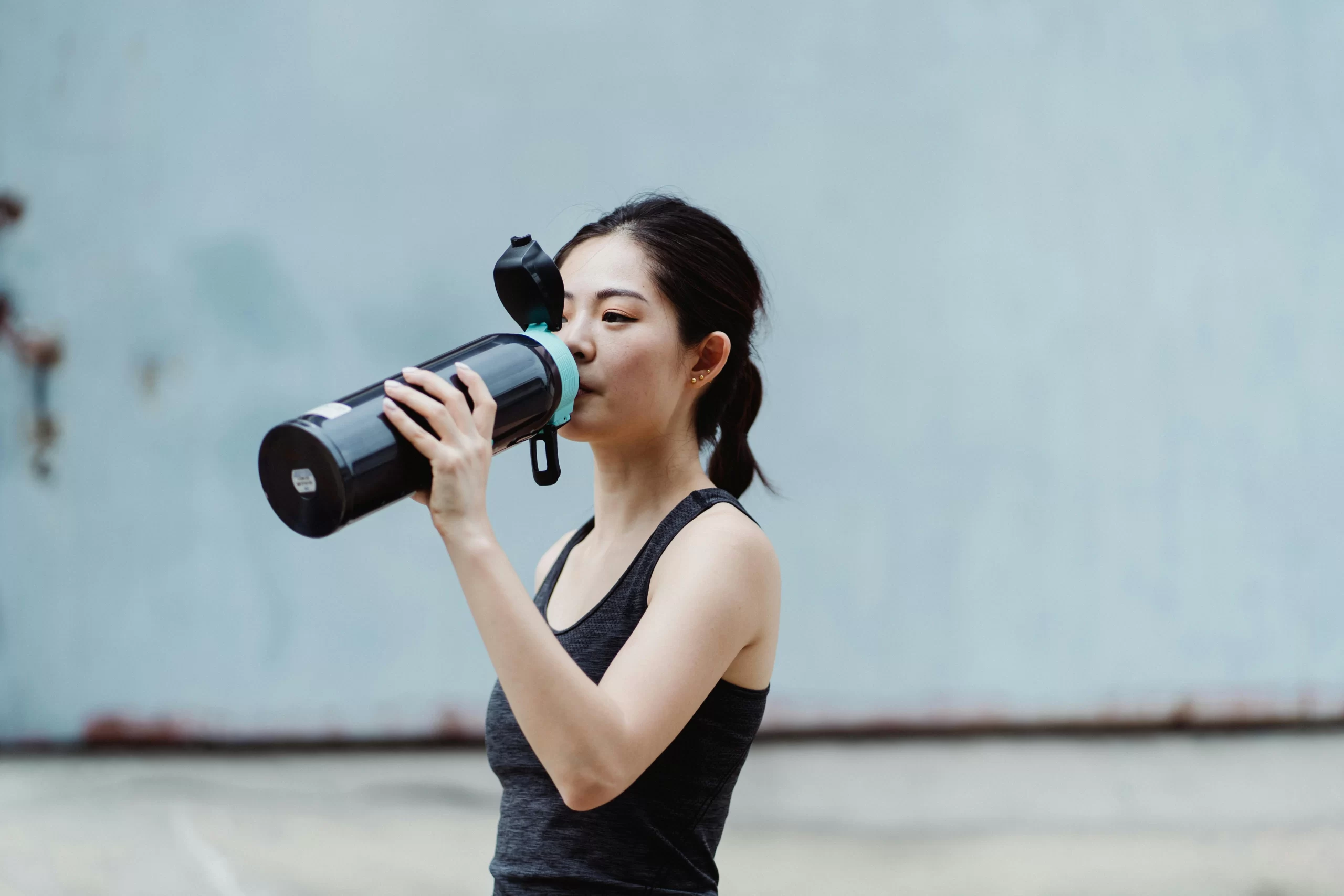 A young female athlete drinking water.